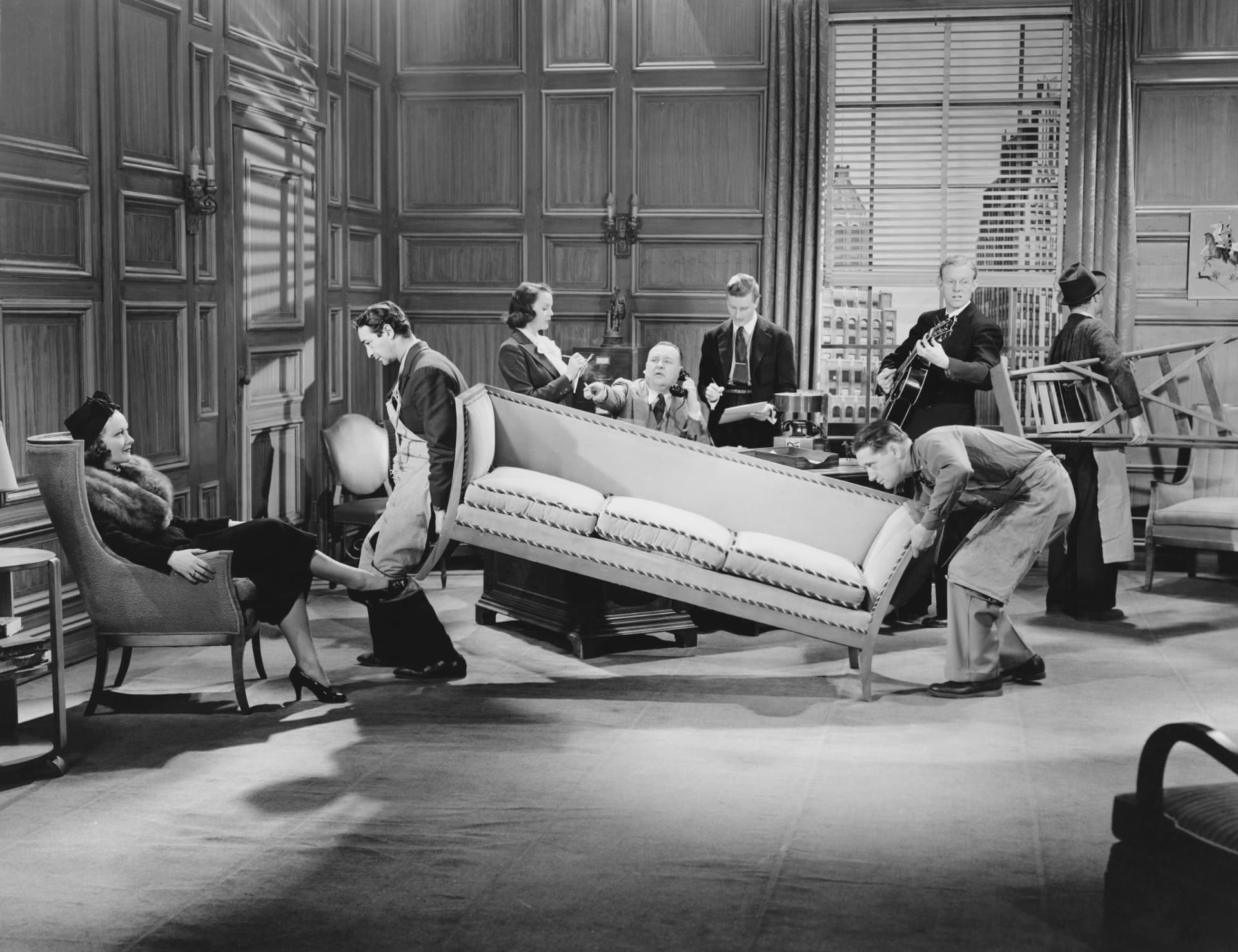 An office team attempting to move a large sofa